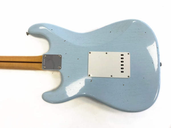Back of light blue electric guitar body with cream plastic cover plate and natural wood neck with skunk stripe, showing wear and vintage finish details