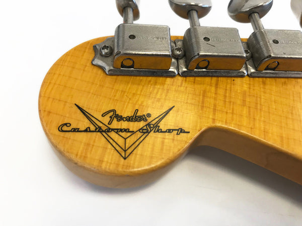 Close-up of Fender Custom Shop logo and vintage tuning machines on natural wood guitar headstock