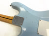 Close-up of light blue electric guitar body back with visible wear, four-screw chrome neck plate, and maple neck with dark stripe, showing aging and finish checking.