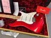 Red Fender Stratocaster electric guitar with maple neck and white pickguard in a plush red velvet-lined hardshell case with Fender owner's manual and paperwork