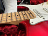 Close-up of red electric guitar neck and strings with maple fretboard and white pickguard in plush red case at Coffee House Guitars