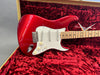 Red electric guitar with maple fretboard and white pickguard in red velvet-lined hardshell case