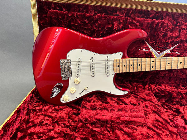 Red electric guitar with maple fretboard and white pickguard in red velvet-lined hardshell case
