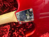 Close-up of red electric guitar neck plate with serial number R953863 and Fender logo, resting on red plush fabric.