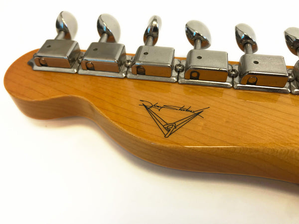 Close-up of maple guitar headstock with vintage-style tuning machines and unique signature logo on back of neck.