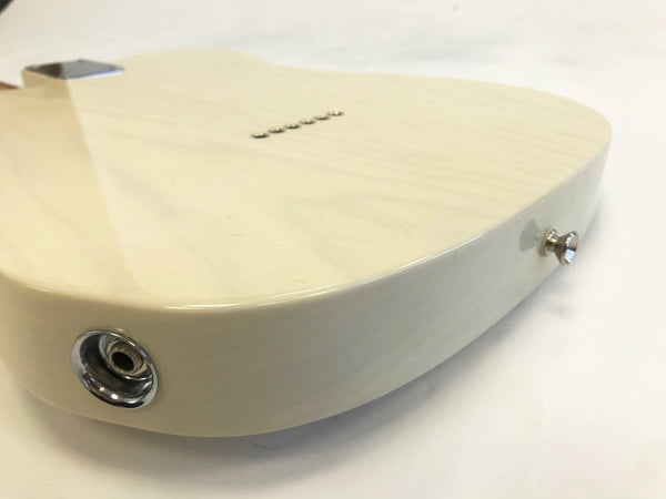 Close-up of cream-colored electric guitar body showing input jack and strap button with smooth glossy finish