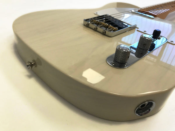 Close-up of cream-colored electric guitar body showing chrome bridge, control knobs, and output jack on white background