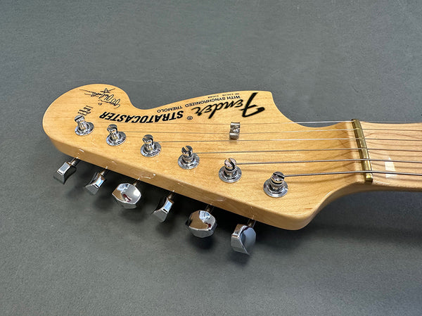 Close-up of Fender Stratocaster maple guitar headstock with chrome tuning pegs and string retainer on gray background