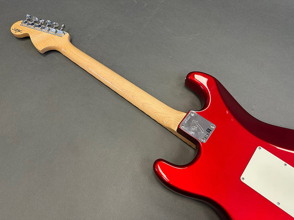 Red Fender Stratocaster electric guitar back with maple neck and chrome tuning pegs on gray background