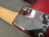 Close-up of red electric guitar neck plate with "GX" engraving and serial number R95865, showing metal screws and natural wood neck from Coffee House Guitars.
