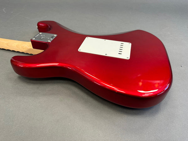 Glossy red electric guitar body with white backplate and natural wood neck on gray background