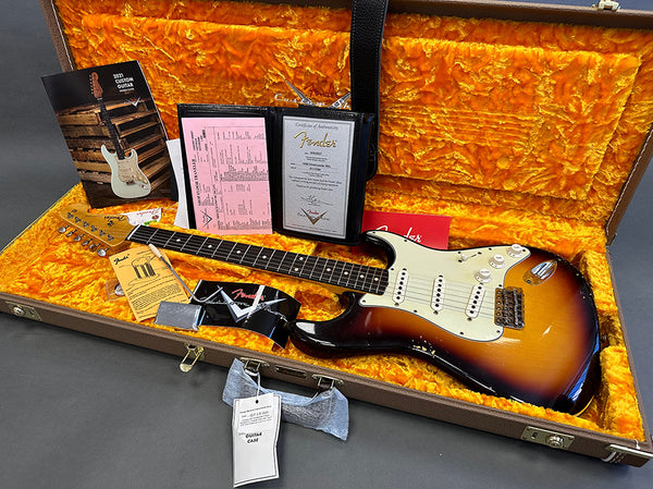 Fender Stratocaster vintage sunburst electric guitar in orange plush-lined hard case with certificate of authenticity, manuals, and accessories