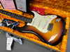 Fender Stratocaster electric guitar with sunburst finish and white pickguard in orange plush-lined hardshell case with Fender certificates and manuals visible