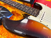 Close-up of vintage sunburst electric guitar body and fretboard with white pickups and pickguard on orange plush guitar case interior