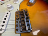 Close-up of electric guitar bridge and strings on sunburst body with white volume knob and pickups