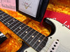 Close-up of Fender Custom Shop electric guitar neck and body in orange plush guitar case with Fender certificate and documents