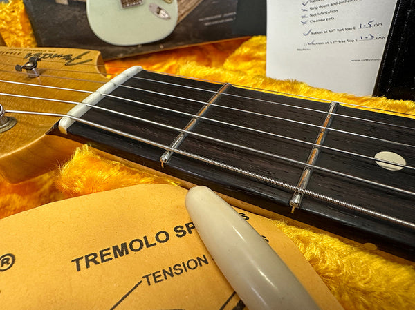 Close-up of Fender guitar neck and fretboard with tremolo spring tension guide and guitar case interior lining in background