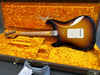 Vintage Fender Stratocaster electric guitar in sunburst finish with maple neck, lying in plush yellow-lined Fender custom shop hard case.