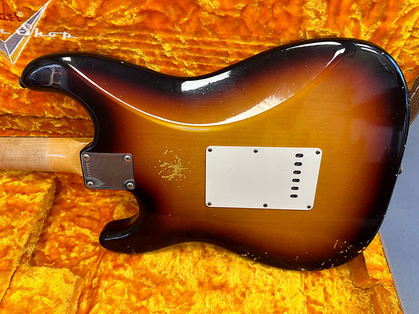 Vintage sunburst electric guitar back with white plastic tremolo cover and visible wear marks inside orange plush guitar case