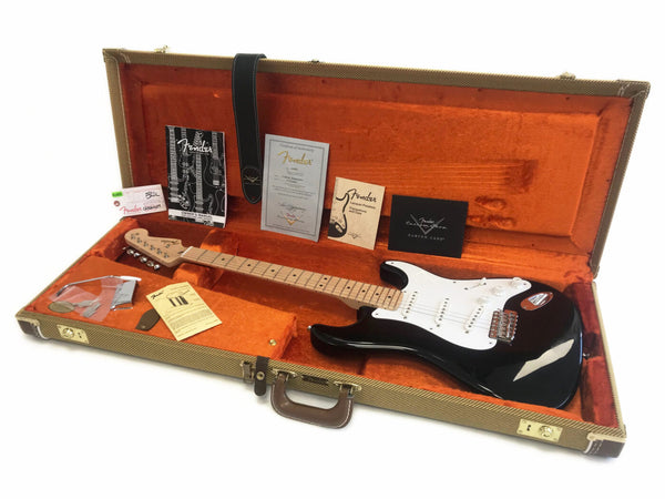 Black Fender Stratocaster electric guitar with maple neck in open vintage tweed hardshell case with orange plush interior, owner's manual, certificate of authenticity, Fender Custom Care card, and guitar accessories