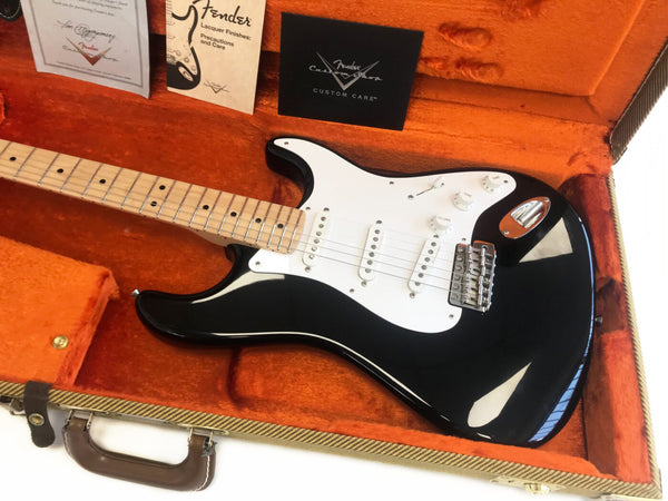 Black Fender Stratocaster electric guitar with white pickguard and maple neck in orange plush-lined Fender tweed case with Fender Custom Care cards