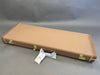 Brown rectangular hard guitar case with gold latches and leather handle on gray background