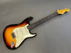 Vintage Fender Stratocaster electric guitar with sunburst finish and rosewood fretboard on gray background