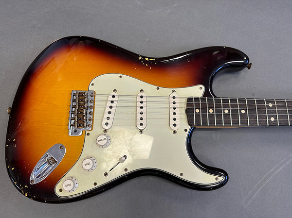 Vintage sunburst electric guitar with three single-coil pickups and white pickguard showing worn and chipped areas on body
