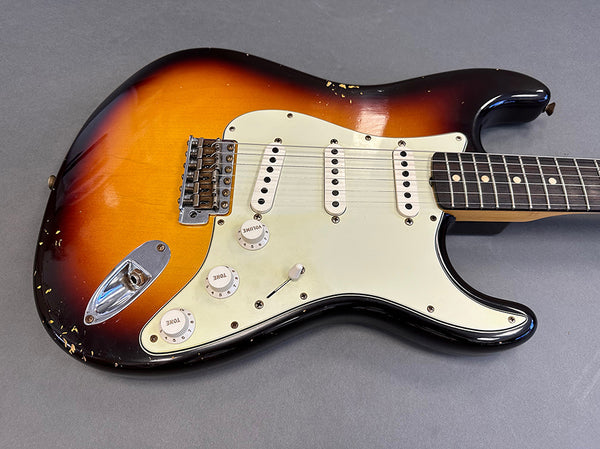 Vintage sunburst electric guitar with white pickguard and three single-coil pickups, showing wear and scratches on the body, from Coffee House Guitars.