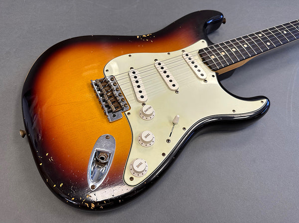 Vintage sunburst electric guitar with three single-coil pickups and white pickguard on gray background