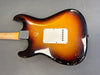 Vintage sunburst electric guitar body showing rear view with worn finish and white plastic backplate on gray background