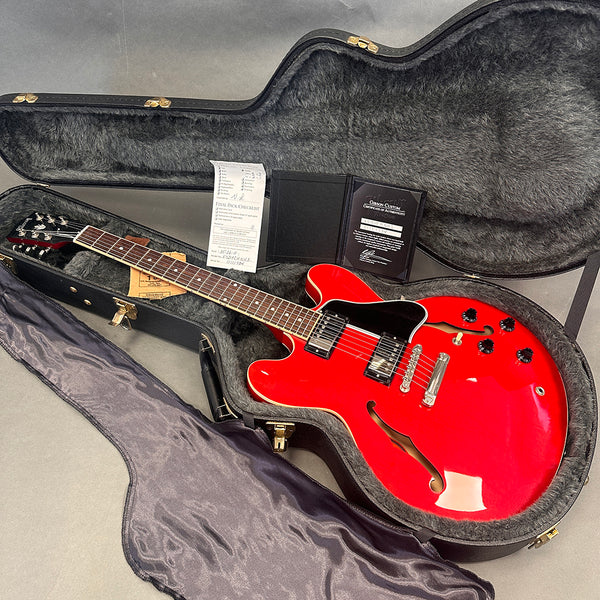 Red Gibson semi-hollow electric guitar in black plush-lined hard case with certificate of authenticity and final pack checklist papers