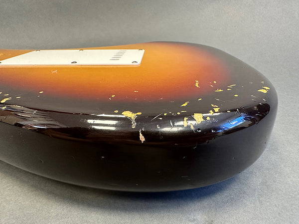 Close-up of worn sunburst electric guitar body with chipped paint and scratches showing vintage wear