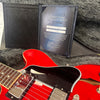Gibson Custom Certificate of Authenticity displayed in open black folder with red electric guitar and black pickguard in case interior with gray plush lining