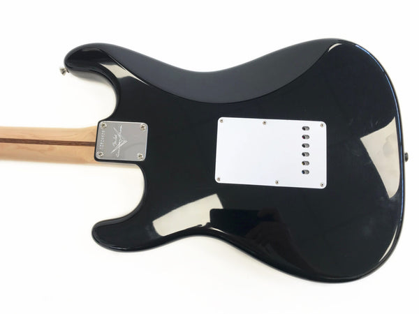 Black Fender Stratocaster electric guitar back view with maple neck and white tremolo cavity cover plate on white background