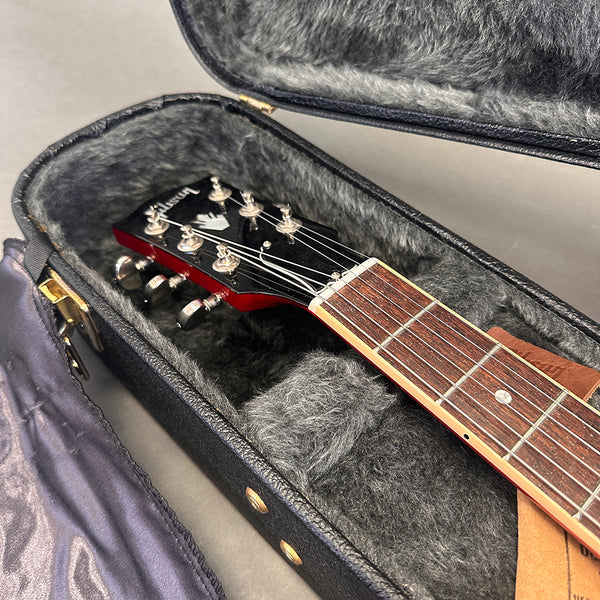 Gibson electric guitar headstock and fretboard inside gray plush-lined black hard guitar case
