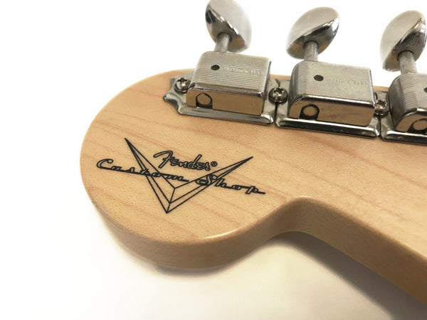 Close-up of Fender Custom Shop guitar headstock with vintage-style tuning pegs and Fender Custom Shop logo on maple wood