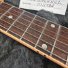 Close-up of rosewood guitar fretboard with metal frets and dot inlays, showing strings and edge binding on electric guitar neck.