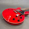 Red semi-hollow electric guitar with black pickguard, chrome bridge, four black control knobs, and cream binding on gray background