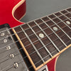 Close-up of red electric guitar fretboard with metal frets, pearl dot inlays, and chrome pickup screws at Coffee House Guitars