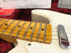 Close-up of maple fretboard and steel strings on white electric guitar with chrome pickup cover in red velvet-lined case at Coffee House Guitars