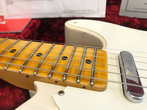 Close-up of maple fretboard and steel strings on white electric guitar with chrome pickup cover in red velvet-lined case at Coffee House Guitars
