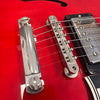 Close-up of red electric guitar bridge and chrome humbucker pickup with six strings and adjustable saddle pieces