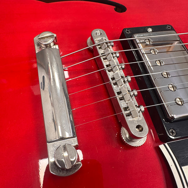 Close-up of red electric guitar bridge and chrome humbucker pickup with six strings and adjustable saddle pieces