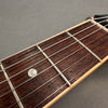 Close-up of rosewood guitar fretboard with metal frets and strings, pearl dot inlay on an acoustic guitar neck