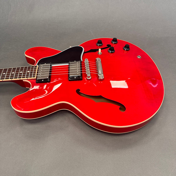 Red semi-hollow electric guitar with black pickguard and dual humbucker pickups on gray background