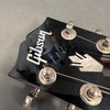 Close-up of black Gibson guitar headstock with silver tuning pegs and mother-of-pearl inlay logo