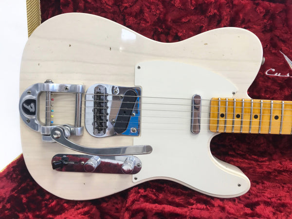 White electric guitar with Bigsby vibrato tailpiece, single-coil pickups, maple fretboard, and chrome hardware on red velvet background
