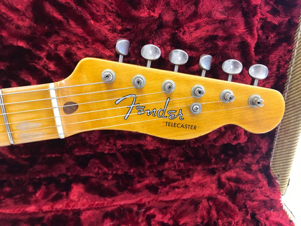 Close-up of Fender Telecaster guitar headstock with tuning pegs and strings on red plush case lining
