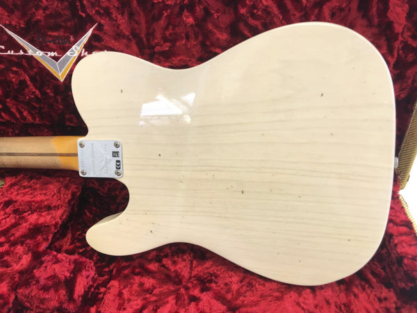 Back of cream-colored electric guitar body with visible wood grain, attached to neck with metal plate, placed on red plush guitar case lining
